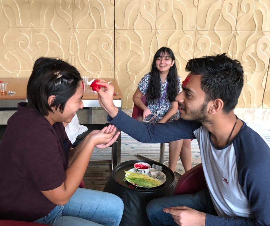 Bishal Sharma applies tika paint for Tanieshaa Shrestha in celebration of Daishan, a Nepali festival. These Nepali students gathered at EC to celebrate the festival together. Photo by Krishna Sharma