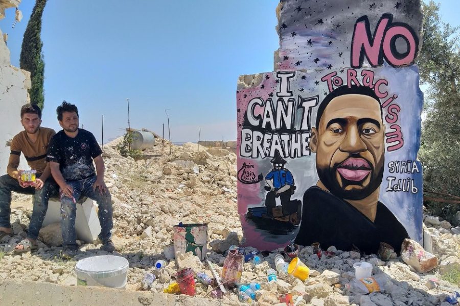 Artists Aziz Asmr and Anis Hamdoun pose next to a graffiti of George Floyd in Idlib, Syria, June 1, 2020. (Photo/ Mohamad Jamalo via REUTERS)